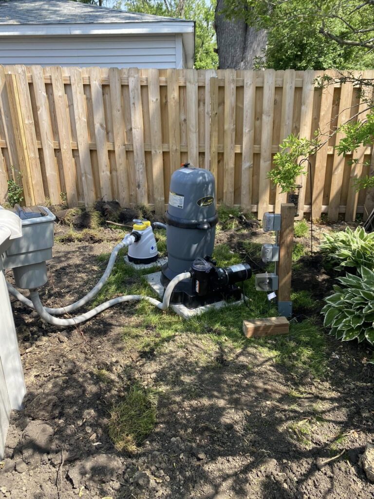 Pool pump and filtration equipment installed beside a backyard fence