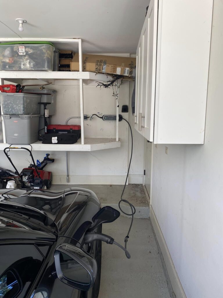 Electric vehicle connected to a wall-mounted charger in a residential garage